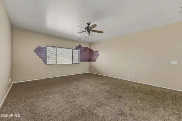 an empty room with windows and ceiling fan