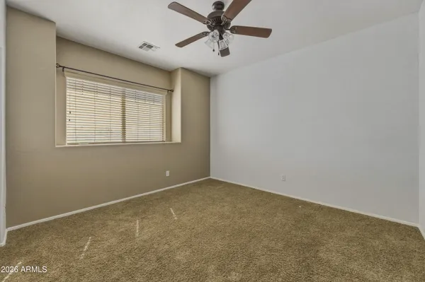 an empty room with chandelier fan and windows