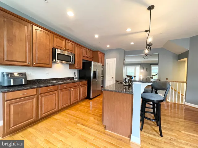 a kitchen with stainless steel appliances granite countertop wooden cabinets a dining table and chairs