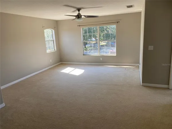 an empty room with windows and ceiling fan