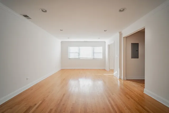 a view of an empty room with wooden floor and windows