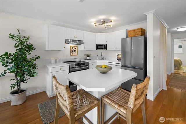 a kitchen with stainless steel appliances granite countertop a dining table chairs and a refrigerator