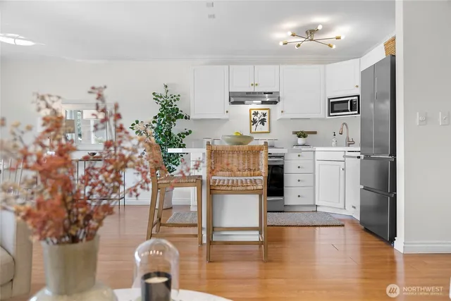 a kitchen with stainless steel appliances granite countertop a refrigerator a stove oven and white cabinets with wooden floor