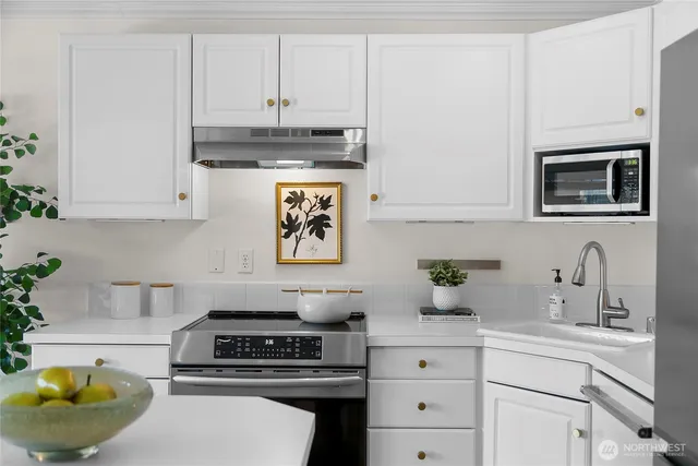 a kitchen with stainless steel appliances a stove a white cabinets and a sink
