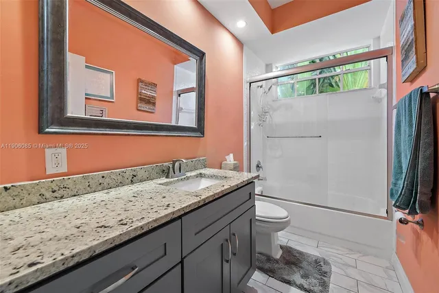 a bathroom with a granite countertop sink toilet and shower