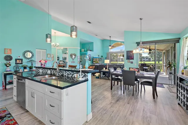 a kitchen with stainless steel appliances granite countertop a stove a refrigerator a dining table and chairs with wooden floor