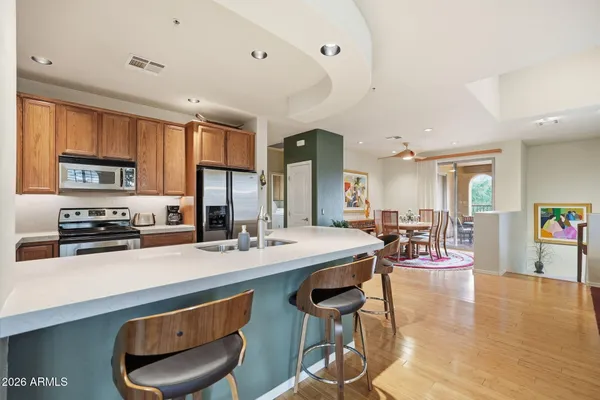 a kitchen with stainless steel appliances granite countertop a stove top oven a sink a dining table and chairs with wooden floor