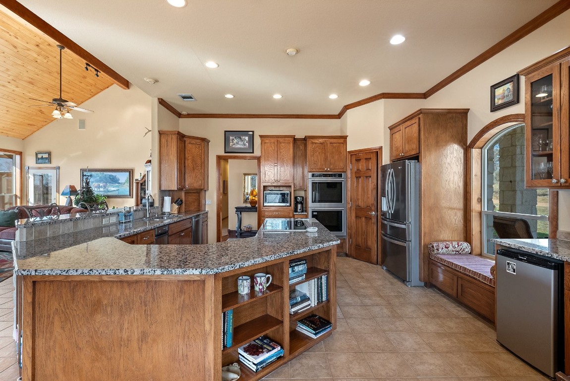 8095 Ranch To Market Road 2618 Fredonia, TX 76842 - Photo 26 of 39 a kitchen with stainless steel appliances kitchen island granite countertop a refrigerator a stove and a sink with wooden floor
