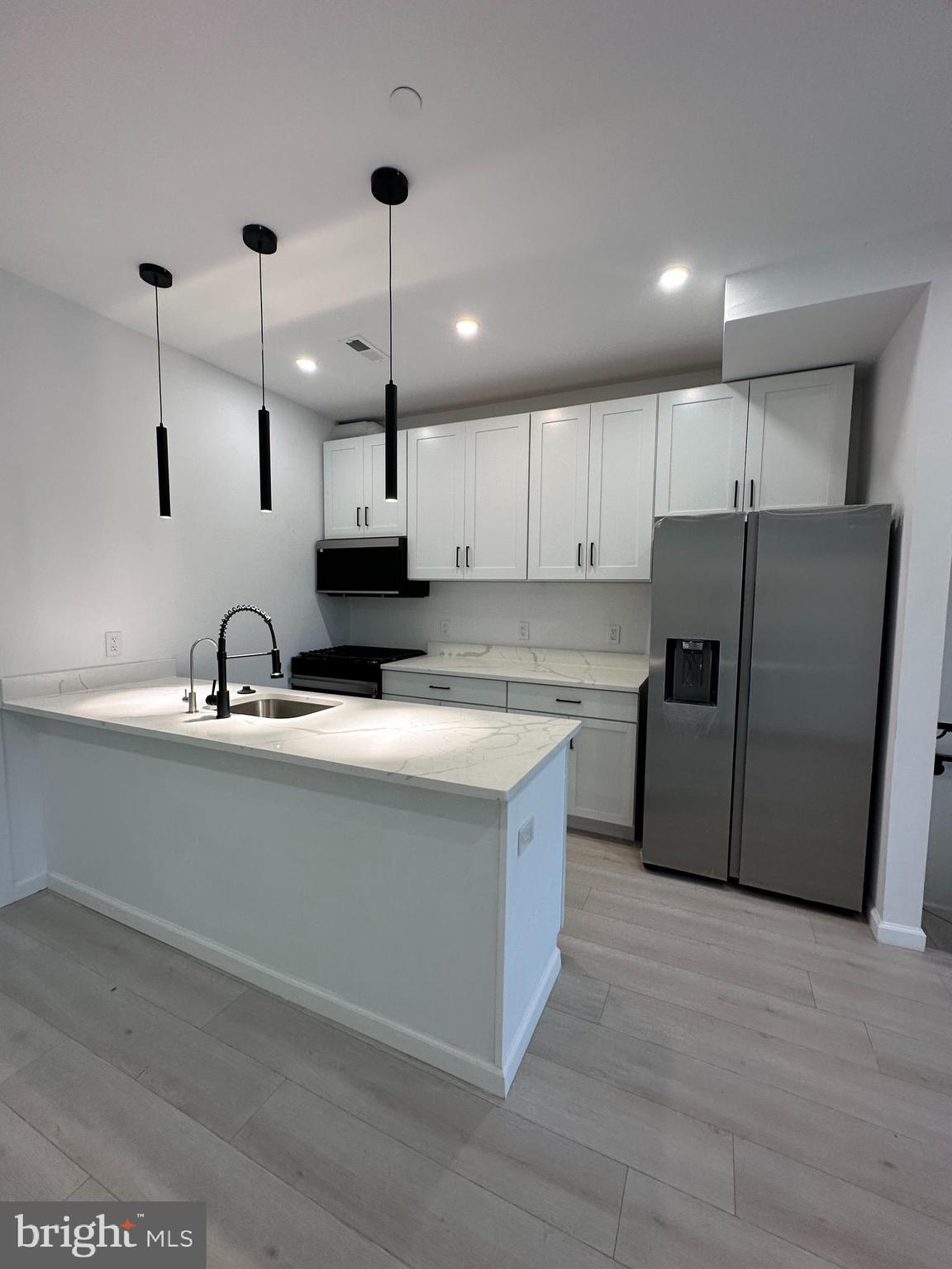 1925 H Street Northeast, Unit 3 Washington, DC 20002 - Photo 6 of 33 a kitchen with stainless steel appliances granite countertop a sink a stove a refrigerator and island with wooden floor