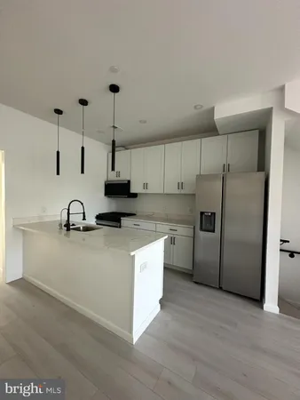 a kitchen with stainless steel appliances granite countertop a sink a stove a refrigerator and island with wooden floor