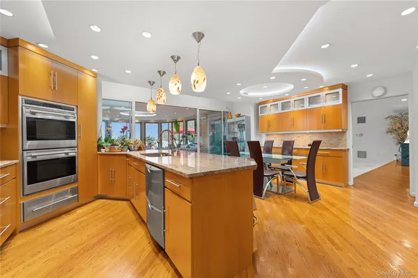 a kitchen with stainless steel appliances granite countertop a stove top oven a sink a dining table and chairs with wooden floor