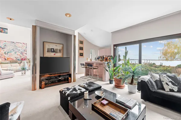 a living room with furniture a flat screen tv and a floor to ceiling window
