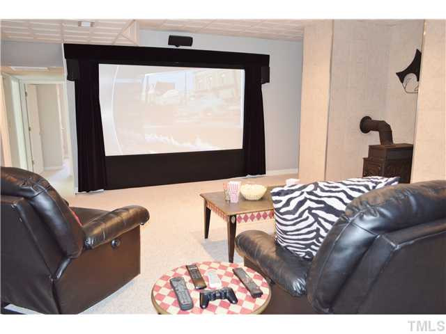 2405 Countrywood Road Raleigh, NC 27615 - Photo 15 of 25 Downstairs is the spacious media/bonus room. It has a huge built-in media screen with an overhead projector. All the equipment goes with the home! The kids/parents will love watching movies or playing video games here! There is also a fancy wood stove. Media Room
