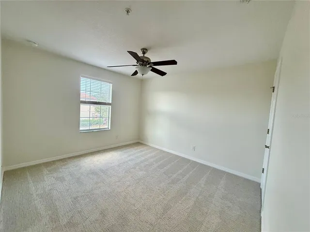 an empty room with a window and a ceiling fan