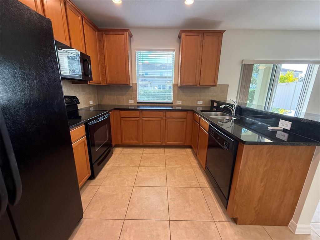 2090 Water Tupelo Way Ocoee, FL 34761 - Photo 29 of 43 a kitchen with granite countertop stove top oven microwave and sink