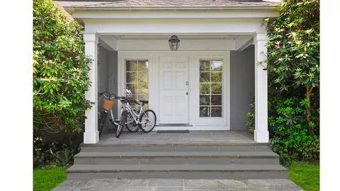 a view of a wooden house with a small yard plants and large tree
