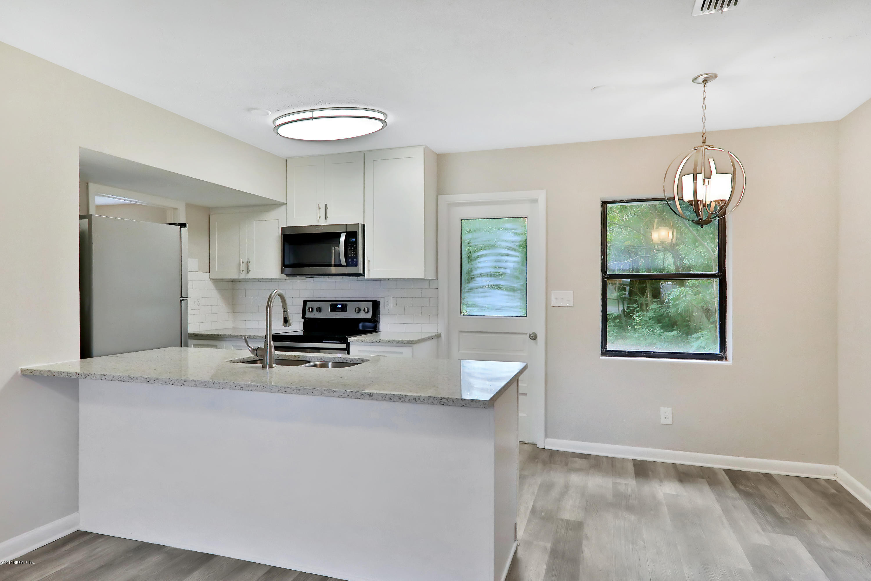 10512 Stone Road Jacksonville, FL 32246 - Photo 8 of 22 a kitchen with kitchen island granite countertop a stove and a wooden floor