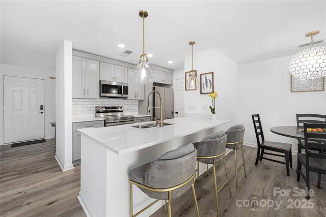 a kitchen with kitchen island a dining table chairs and a refrigerator