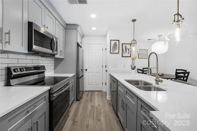 a kitchen with stainless steel appliances granite countertop a sink a stove top oven and refrigerator