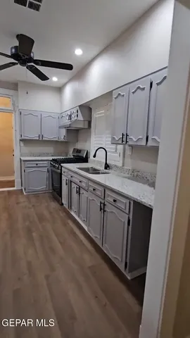 a view of a kitchen with a refrigerator a ceiling fan and wooden floor
