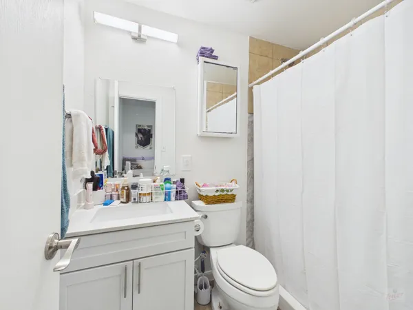a bathroom with a sink a toilet a mirror and shower curtain