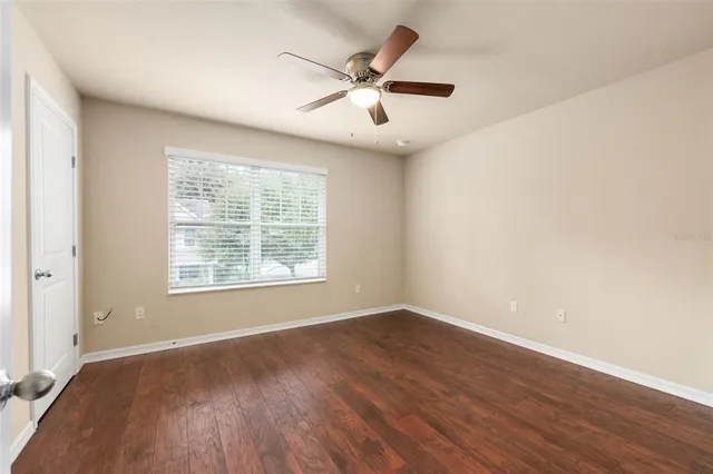 a view of an empty room with wooden floor and a window