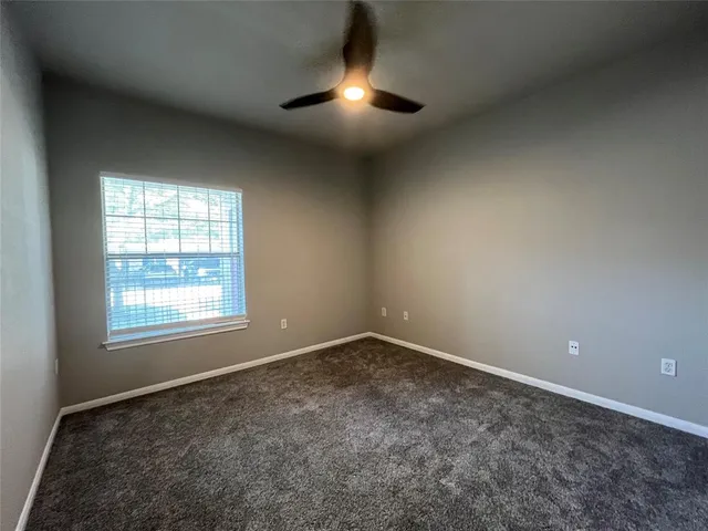 an empty room with chandelier fan and windows