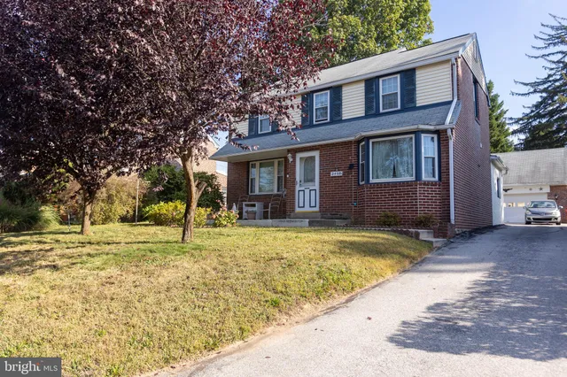 a view of a house with a yard and large tree