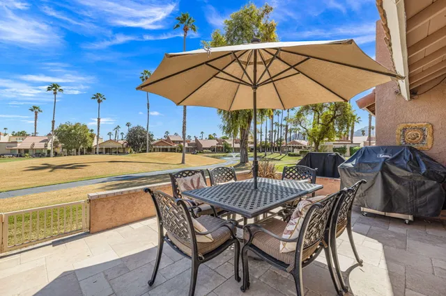 a view of patio with chairs and table under an umbrella