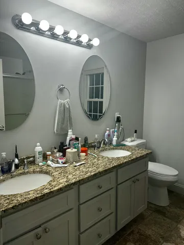 a bathroom with a granite countertop double vanity and a mirror