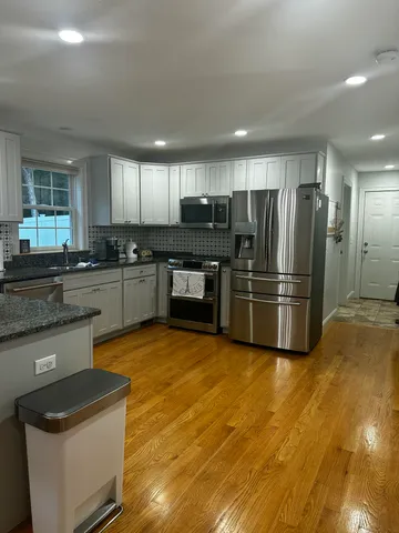 a kitchen with granite countertop a refrigerator and a stove top oven