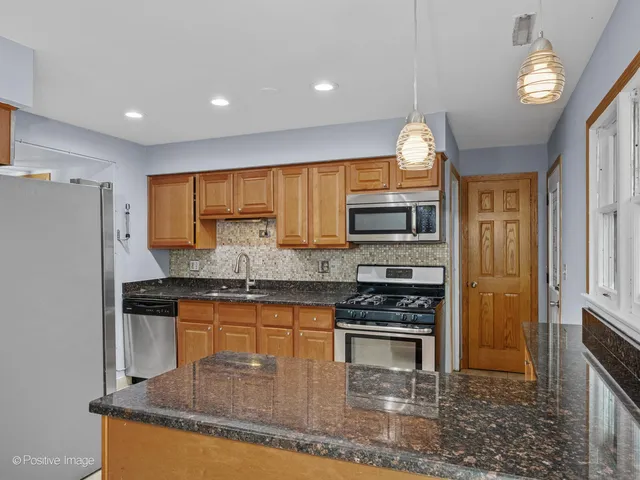 a kitchen with stainless steel appliances granite countertop a stove a sink and a refrigerator