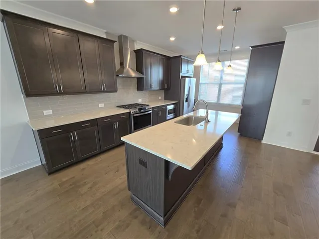 a kitchen with stainless steel appliances granite countertop a sink a stove and a wooden floors