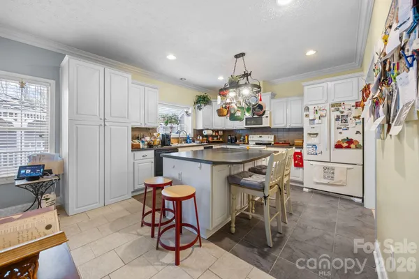 a kitchen with stainless steel appliances a dining table chairs refrigerator and sink