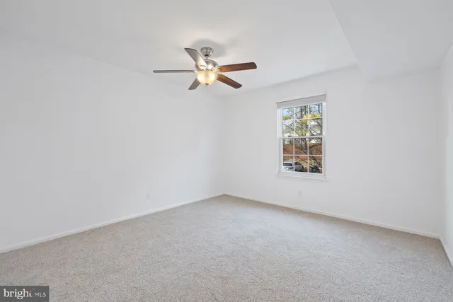 an empty room with a window and ceiling fan