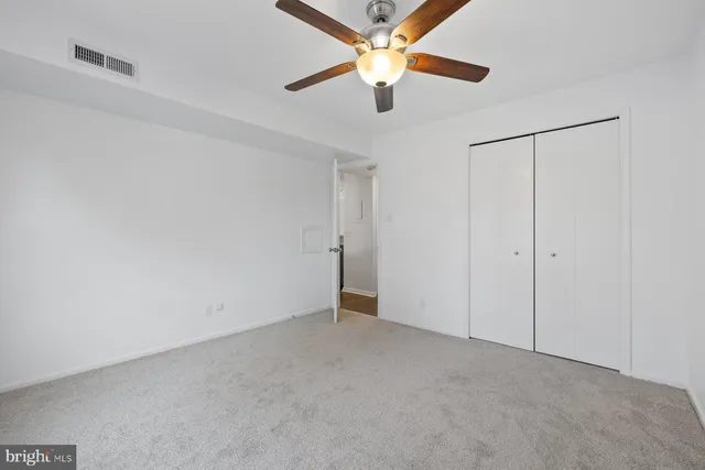 an empty room with closet and a chandelier fan