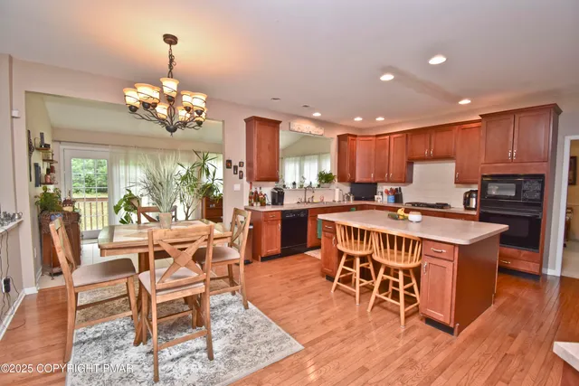 a kitchen with stainless steel appliances granite countertop a stove top oven a refrigerator a dining table and chairs with wooden floor