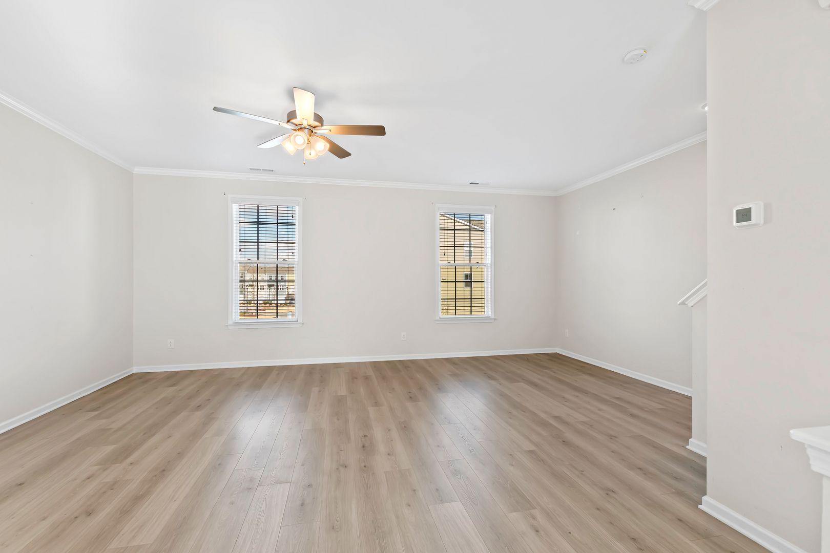 6103 Kayton Street Raleigh, NC 27616 - Photo 23 of 45 an empty room with wooden floor ceiling fan and windows
