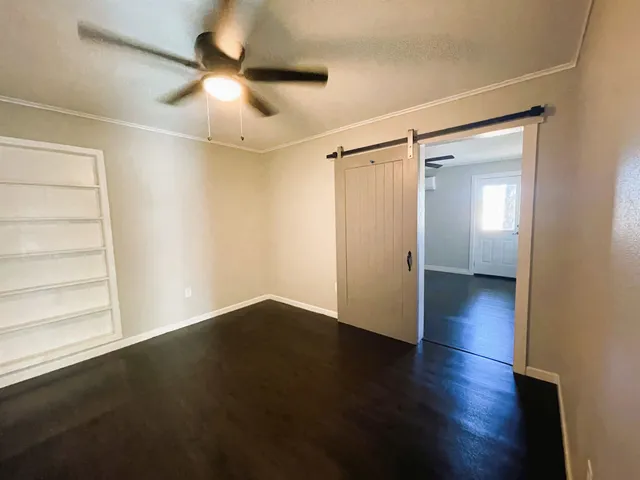 an empty room with wooden floor fan and windows