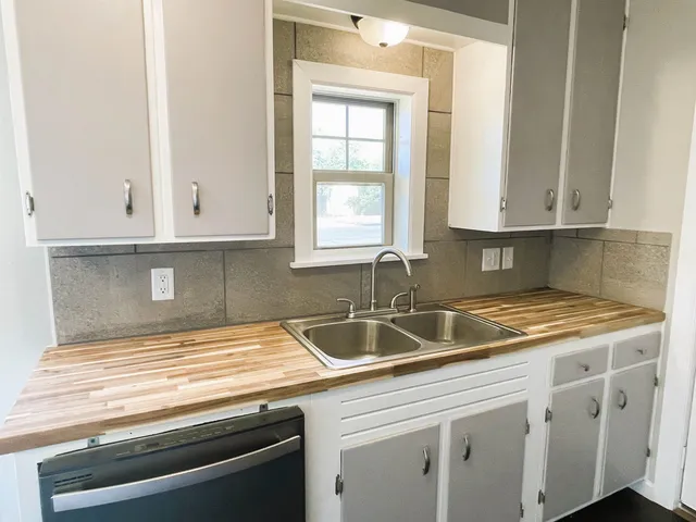 a kitchen with granite countertop white cabinets and a sink