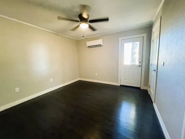 an empty room with wooden floor and ceiling fan