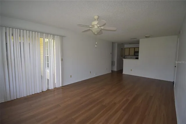 an empty room with wooden floor fan and windows