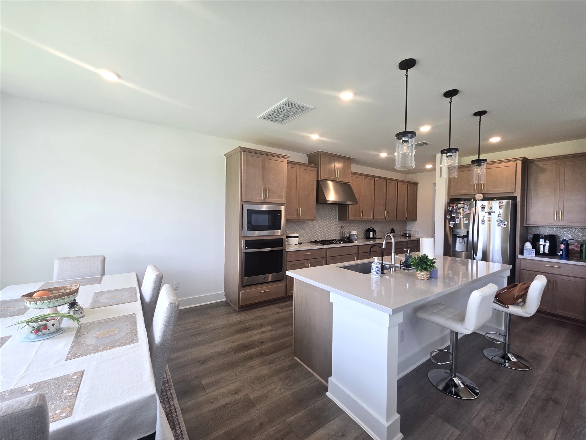 124 Ribera Drive Liberty Hill, TX 78642 - Photo 9 of 40 A contemporary kitchen and dining space featuring an island, pendant lighting, and modern appliances.