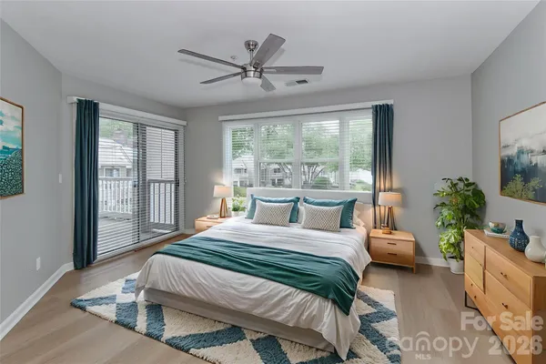 a bedroom with a balcony a bed a chandelier and a large window