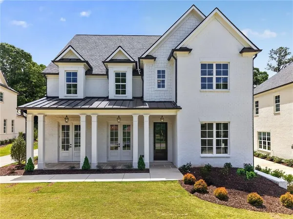a view of a white house with large windows and a yard