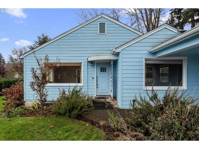 a view of a house with a small yard plants and large tree