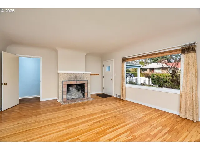 a view of empty room with wooden floor and fireplace