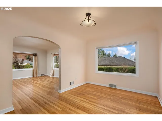 a view of empty room with window and wooden floor