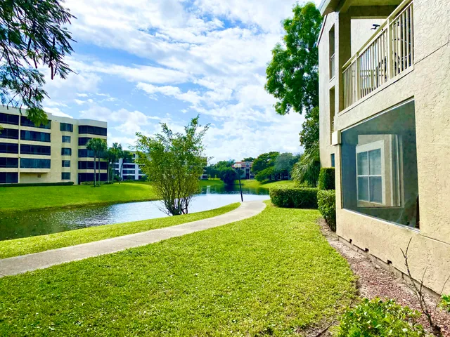 a view of a house with a big yard potted plants and large tree
