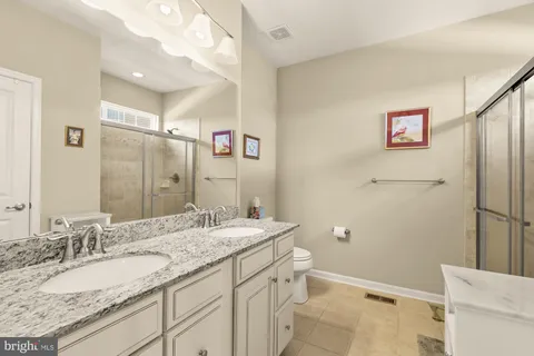 a bathroom with a granite countertop sink mirror vanity and toilet